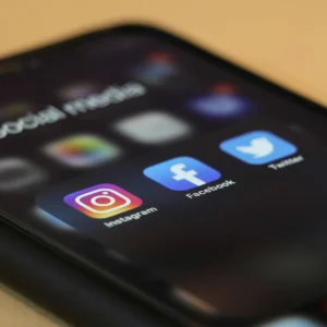 Partie d'un écran de téléphone portable affichant les logos de réseaux sociaux d'Instagram, de Facebook et de Twitter.